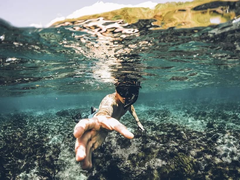 A diver reaching towards the camera above a reef