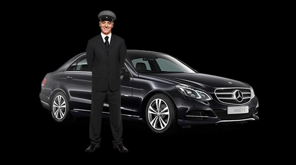 A uniformed chauffeur standing beside a black saloon car